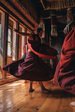 Jakar Dzong, Bhutan - 24 September 2025: View of a monk, clad in deep maroon robes, twirling gracefully within the wooden confines of a traditional Bhutanese building.
