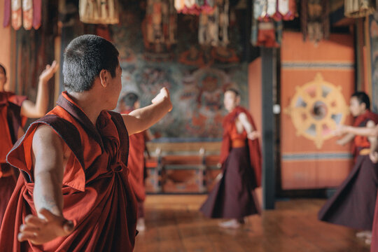 Jakar Dzong, Bhutan - 24 September 2025: View of monks adorned in rich maroon robes engaged in a vibrant, ritualistic dance within the ornately decorated temple walls.