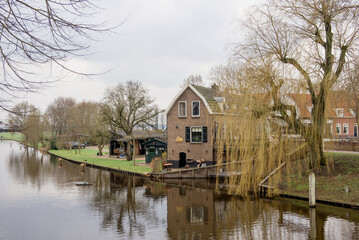 Obraz premium Elburg, Netherlands, April 10 2018: A picturesque canal view with charming houses reflecting on the water