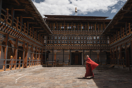 Jakar Dzong, Bhutan - 24 September 2025: View of a monk's bright red robes in striking contrast against the muted tones of the ancient Jakar Dzong's courtyard.