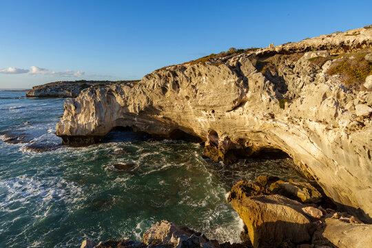 Dramatic coastline near Waenhuiskrans Cave, Arniston: towering cliffs meet ocean waves in pristine Overberg seascape, Western Cape, South Africa. Ideal for nature, travel, and adventure visuals.