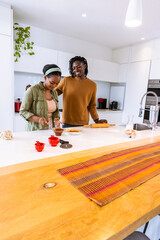 African American couple preparing food at modern kitchen island with rolling pin and mixing bowl © wavebreak3