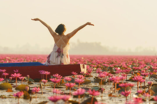 Rear view of a young woman with her arms outstretched sitting in a boat, Red Lotus Sea (Talay Bua Daeng), Udon Thani, Northeast Thailand, Thailand