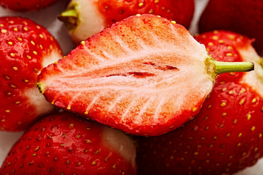 Full frame close-up of a halved strawberry on top of a stack of fresh strawberries