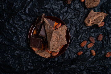 different various  of chocolate with natural cocoa beans at black background