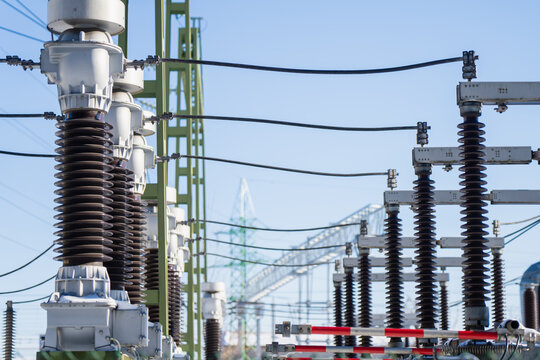 High voltage substation detail with tall ceramic insulators, busbars and overhead conductors on steel frames, power grid infrastructure and energy security theme