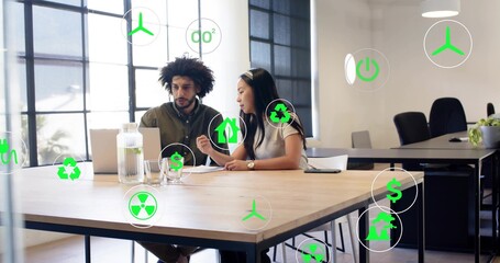 Reviewing two coworkers in business shirts examining laptop and papers in office, with eco icons © vectorfusionart