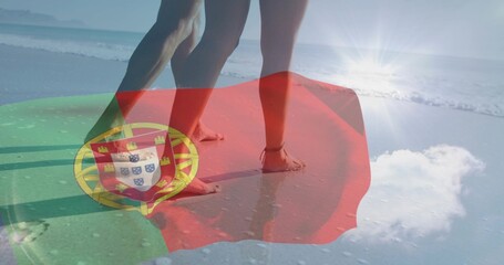 Naklejka premium Standing couple showing legs, bare feet at beach edge, bikini, swim trunks, Portuguese flag overlay