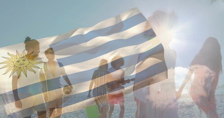 Naklejka premium Walking 8 friends in swimwear on beach at sunset holding guitar ball board Uruguay flag overlay