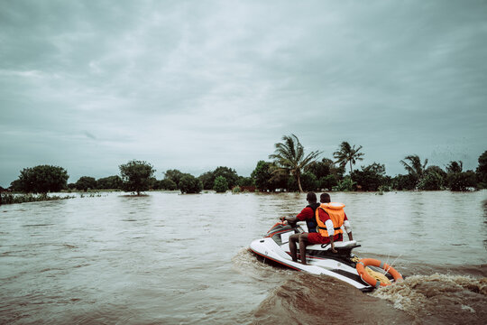Manhica, Mozambique - 20 January 2026: View of a rescue team speeding across the murky, floodwaters towards submerged trees under a heavy, overcast sky.