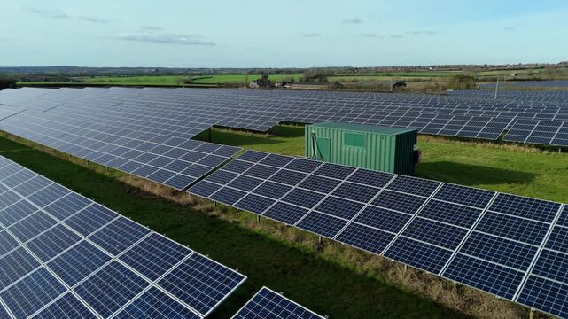 Close-up aerial drone view of a vast photovoltaic solar array integrated with a high-capacity battery energy storage system (BESS) site in the UK.