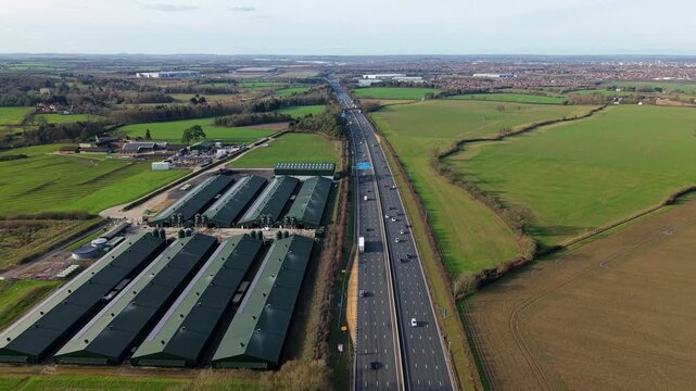 High angle aerial drone view of modern livestock agricultural barns and a biogas renewable energy plant near the M1 motorway in Northampton United Kingdom.