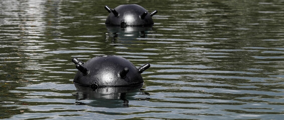 Two partially submerged mines with protruding parts in the dark water. 1908/1939 Soviet naval...