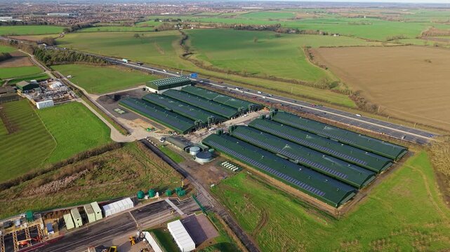 High angle aerial drone view of modern livestock agricultural barns and a biogas renewable energy plant near the M1 motorway in Northampton United Kingdom.