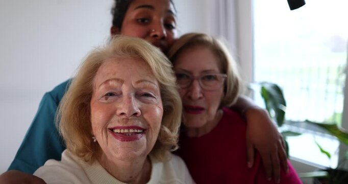 Joyful moment with three diverse women of different generations, an elderly lady, her daughter, and granddaughter, laughing and taking a selfie together, capturing family love and unity
