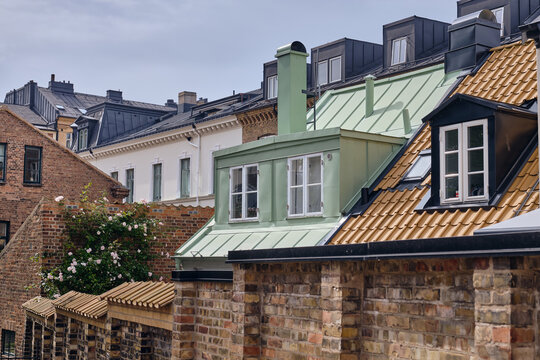 Helsingborg, Sweden - 12 August 2025: View of rooftops cascading with hues of terracotta, slate, and soft green against a backdrop of pale skies and brick walls.