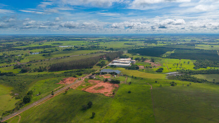 Obraz premium Aerial view of a serene landscape with green fields and a large building complex under a blue sky