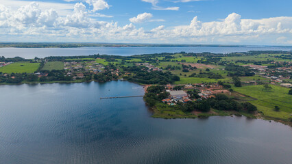 Fototapeta premium Aerial view of a serene landscape with a lake, green fields, and a small town under a blue sky