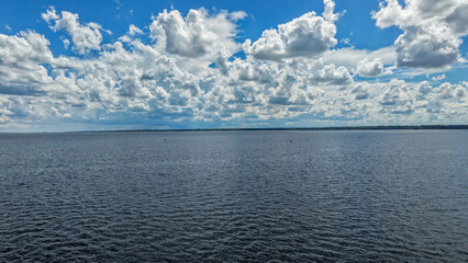 A serene ocean landscape with a blue sky and white clouds on a sunny day