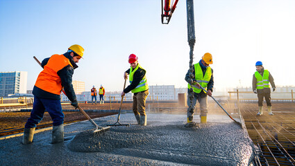 Pouring fresh concrete at a construction site, concrete pump, workers in personal protective equipment,