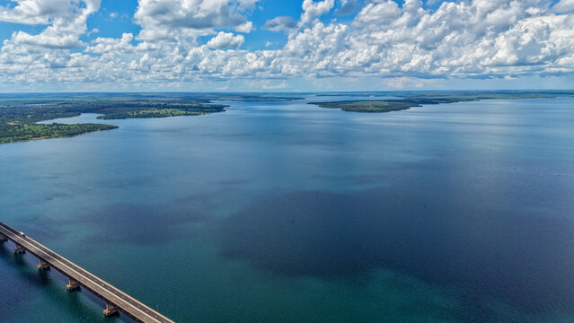 Aerial view of a serene body of water with a bridge and islands under a cloudy sky