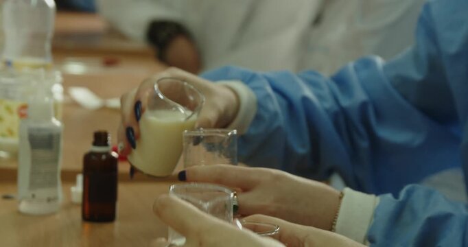 Laboratory worker pouring liquid into beaker scientific experiment