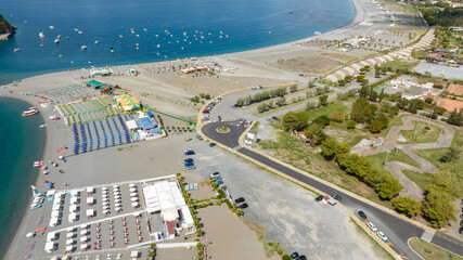 Fototapeta premium Aerial view of Praia a Mare beach, located in the province of Cosenza, Calabria, southern Italy. There are many beach resorts along the coast overlooking the Tyrrhenian Sea. Summer sunny morning.