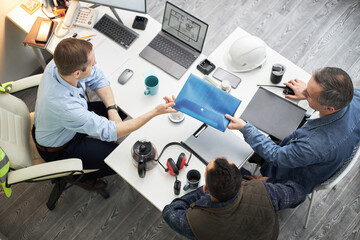 Three middle aged men, including Caucasian and possibly multiethnic individuals, sitting at office...
