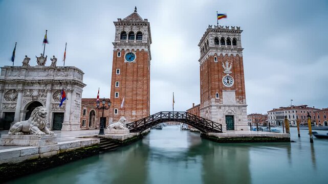 Symmetrical brick towers flanking canal entrance with stone lions and arched bridge