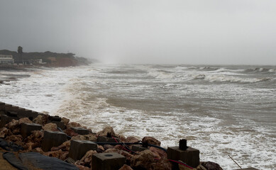 Dramatic Waves Crashing Against Rocky Beach Shore on a Cloudy Day.