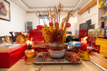 Traditional Vietnamese ancestral altar with incense sticks, candles, and offerings on dining table © chuangxin