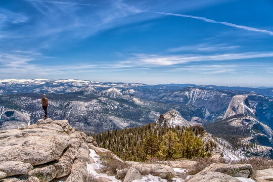 A person is standing on a mountain top, looking out over a beautiful landscape