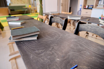 Empty classroom with stacked books and dusty wooden desks in soft daylight