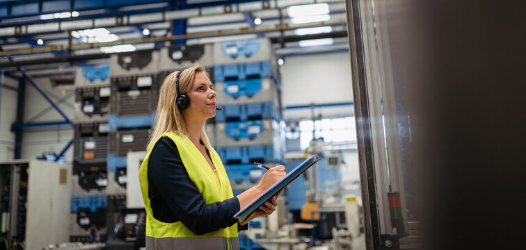 Female factory supervisor checking products in industrial production hall.