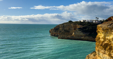 Beautiful sandy beach with red rocks and cliffs. Sunset at dusk with shallow waves on the Atlantic coast in Praia do Poco Velho, Praia da Falesia, Algarve, Portugal