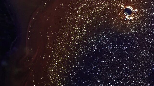 Abstract macro motion of tiny golden bubbles and glitter particles rising from the corner in dark liquid. Elegant fluid transitions with shimmering gold dust and organic shapes. High-quality artistic 