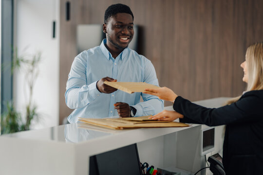 Courier delivering padded envelope to woman at reception desk