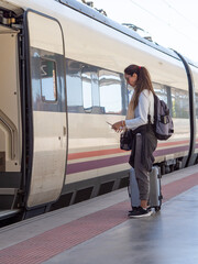 Woman passenger boarding train with luggage at station