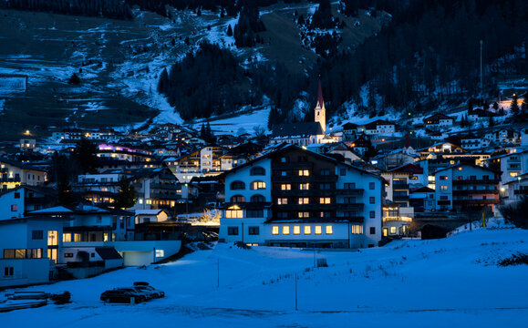 Nauders Village at Winter Evening, Tyrol Austria: Illuminated Houses, Snowy Alps Background