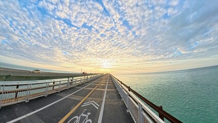 Long ocean bridge and bike lane at sunrise with dramatic cloudy sky