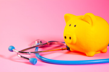 Piggy bank and stethoscope on pink background. Health care concept.