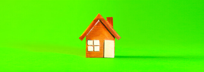 Miniature wooden house on green background. Real estate and property concept