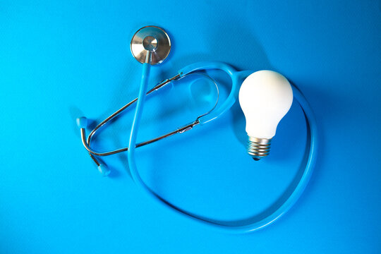Stethoscope and light bulb on blue background. Concept of idea.