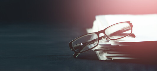 Stack of books and glasses on dark background. Selective focus.