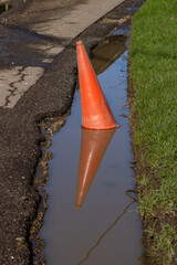 A traffic cone in a water filled pothole, on a country road in Sussex