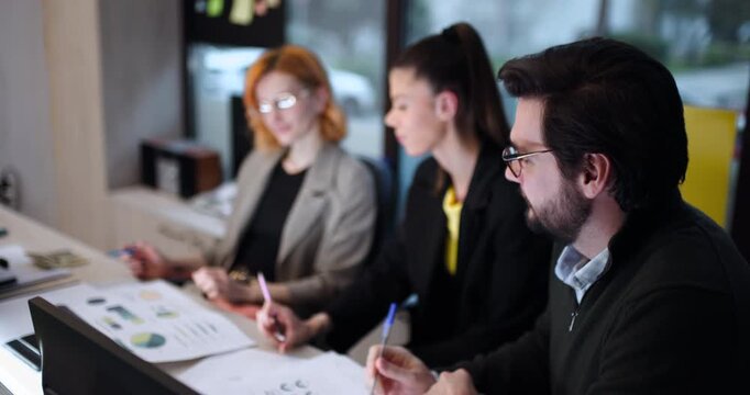 Team members discuss project ideas at a modern office setting during the day while sharing notes and designs with each other focused on collaboration and brainstorming