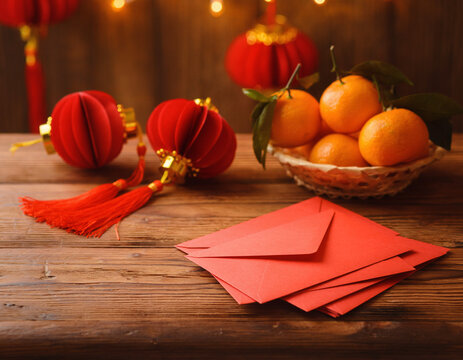 Chinese New Year still life with red lanterns, mandarin oranges and red envelopes on wooden table