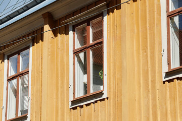 Yellow wooden house facade with windows in sunlight
