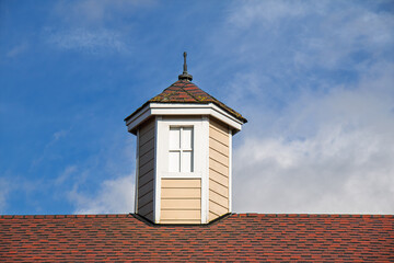 Wooden rooftop cupola with a blue sky and white clouds in the background