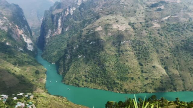 Aerial view of boats navigating the emerald waters of the Nho Que River through the towering cliffs of the Ma Pi Leng Pass in Meo Vac, Ha Giang, Vietnam